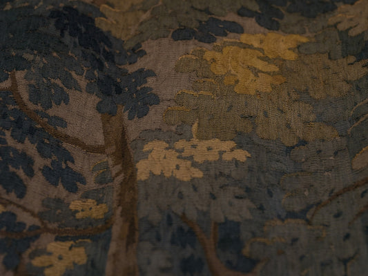 A detailed tapestry depicting a forest scene with trees.