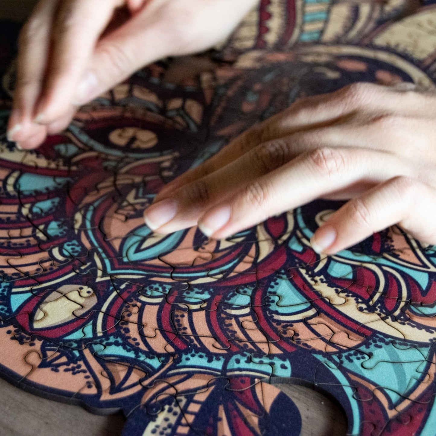 hands holding jigsaw pieces of a Colorful Wolf Wooden Jigsaw Puzzle: Stylized wolf with a vibrant, patterned body. Intricate wooden puzzle