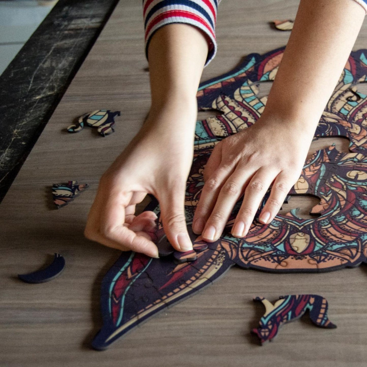 hands holding jigsaw pieces of a Colorful Wolf Wooden Jigsaw Puzzle: Stylized wolf with a vibrant, patterned body. Intricate wooden puzzle
