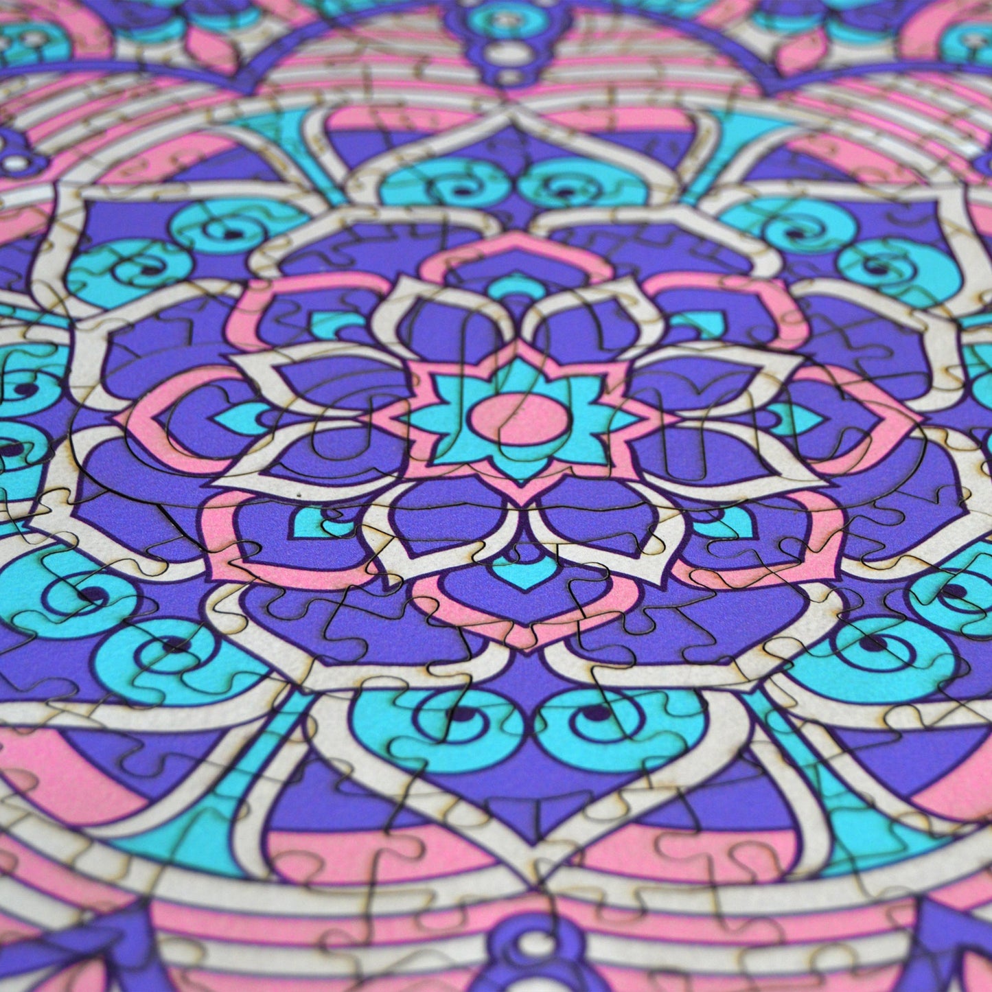hands holding jigsaw pieces of a colorful mandala wooden jigsaw puzzle with a geometrical design.