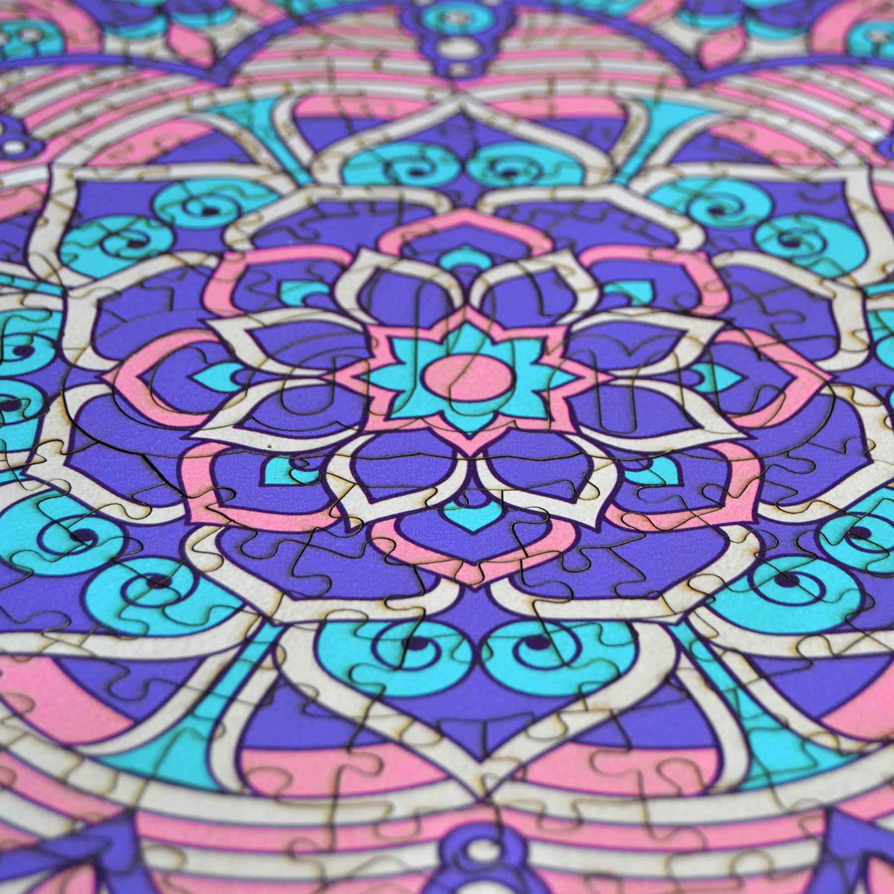 hands holding jigsaw pieces of a colorful mandala wooden jigsaw puzzle with a geometrical design.