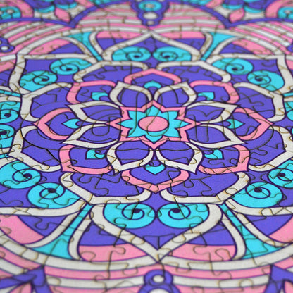 hands holding jigsaw pieces of a colorful mandala wooden jigsaw puzzle with a geometrical design.