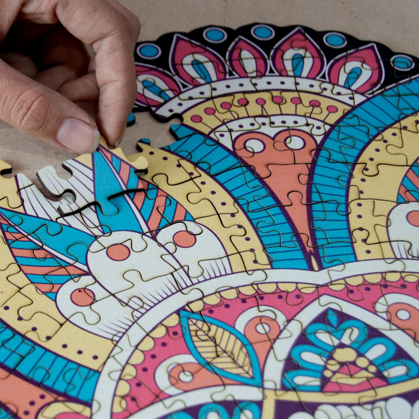 hands holding jigsaw pieces of a colorful mandala wooden jigsaw puzzle with a geometrical design.