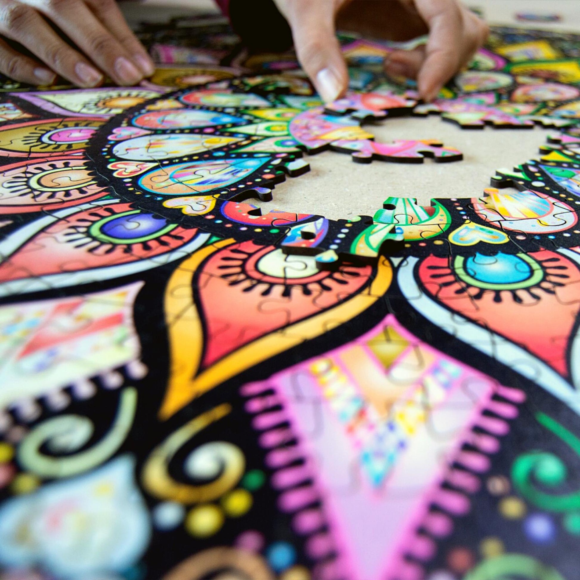 hands holding a colorful jigsaw of a mandala puzzle. Wooden jigsaw, intricate art design.